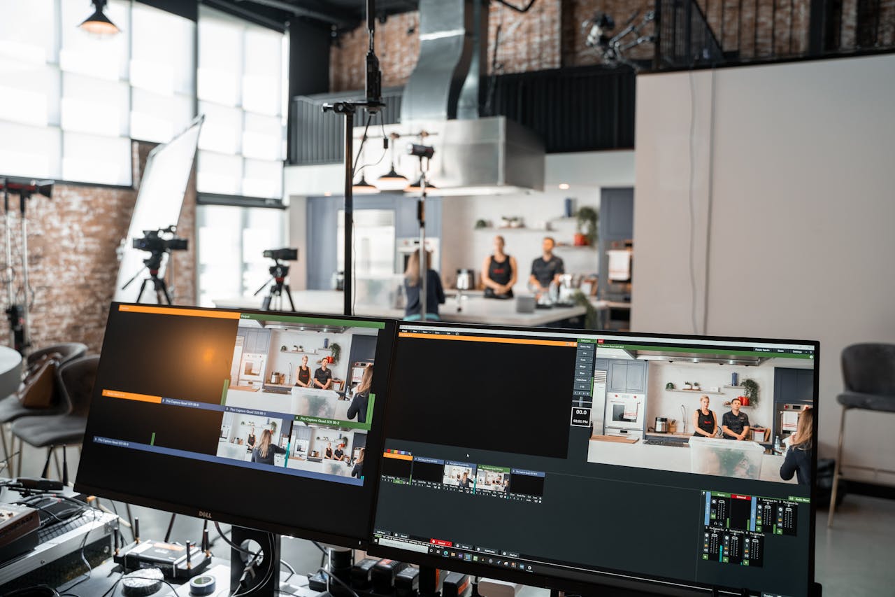 About A dynamic setup in a video production studio with two monitors and a kitchen setting.